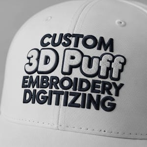 May include: A white baseball cap with the words "CUSTOM 3D Puff EMBROIDERY DIGITIZING" embroidered in navy blue and white. The hat has a curved brim and a structured crown.