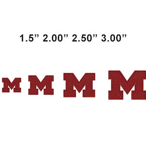 May include: Four embroidered maroon letter "M" patches in varying sizes: 1.5", 2.00", 2.50", and 3.00". Each letter has a classic collegiate block style. The patches are displayed against a white background.