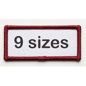 May include: A rectangular patch with a white center and a dark red border. The text "9 sizes" is printed in black, centered on the patch. The patch has a textured appearance.