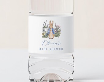以下が含まれることがあります： 白いキャップが付いた透明なプラスチック製のウォーターボトル。青いジャケットを着たウサギの水彩イラストが描かれたラベルが付いています。ラベルには青い筆記体で「Olivia's BABY SHOWER」と書かれています。