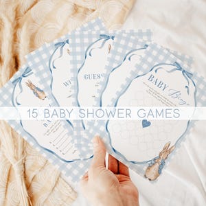 May include: A stack of baby shower games with a blue gingham pattern and watercolor illustrations of a bunny. The games include "Baby Bingo" and "Guess Who?" with the text "15 Baby Shower Games" across the image.
