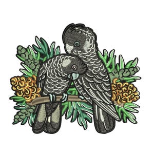 May include: Embroidered patch showing two black cockatoos on a brown branch, with green leaves and yellow-orange flowers. The birds have white and grey detailing, giving a textured look. The patch is set against a white background.