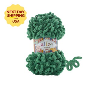 May include: A ball of green Alize Puffy Fine yarn. The yarn is a soft, looped texture. The label reads "Alize Puffy Fine" with the words "Soft & Quick" and "Patented" also visible. The yarn is a vibrant green color.
