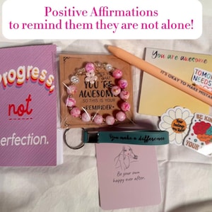 May include: An assortment of self-care items, including a pink and white beaded bracelet, a notebook with "Progress not perfection," and a pen with "It's okay to make mistakes." The image also includes stickers and a keychain.