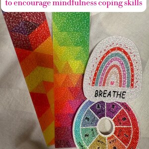 May include: Image features sensory strips and breathing stickers. The strips have textured surfaces with geometric patterns in red, orange, and green. A rainbow-themed sticker says "BREATHE," and a circular sticker reads "CALM DOWN."