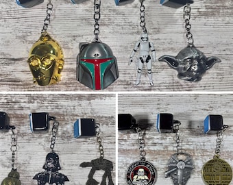 May include: A selection of Star Wars character keyrings. Featuring C-3PO, Boba Fett's helmet, a Stormtrooper, Yoda, BB-8, Darth Vader, an AT-AT walker, a 501st Legion emblem, Millennium Falcon, and Death Star.