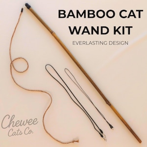 Könnte beinhalten: Bambus-Katzen-Zauberstab-Set mit dem Text "BAMBOO CAT WAND KIT EVERLASTING DESIGN". Das Set enthält einen langen Bambus-Zauberstab, eine braune Schnur und zwei schwarze Kordeln. Das Logo von Chewee Cats Co. befindet sich unten links.