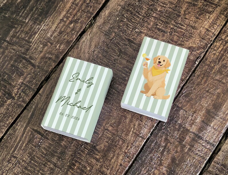 May include: Two small, rectangular boxes with a light green and white striped pattern. One box has the names "Emily & Michael" and the date "06.22.2026" printed on it. The other box features a cartoon golden retriever dog with a cocktail.