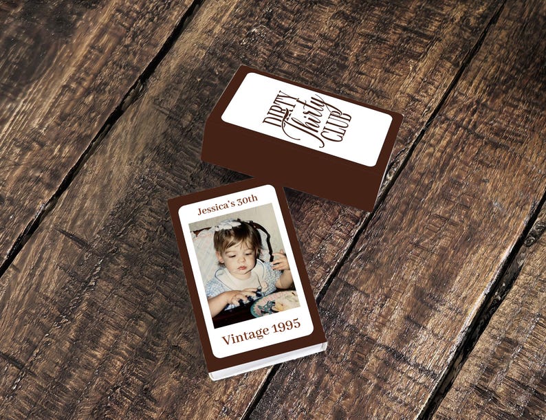 May include: Two brown boxes with white labels. One label reads "Dirty Thirty Club" in a script font. The other box has a photo of a child and the text "Jessica's 30th Vintage 1995". The boxes are on a wooden surface.