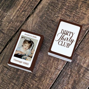 May include: Two brown rectangular boxes are displayed on a wooden surface. One box features a photo of a young child with the text "Jessica's 30th" and "Vintage 1995." The other box has the words "Dirty Thirty Club."