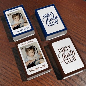 May include: Four small, rectangular boxes. Two boxes are navy blue with white text that reads "DIRTY Thirty CLUB". The other two boxes are brown with a photo of a child and the text "Jessica's 30th" and "Vintage 1995".
