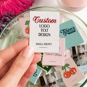 May include: A collection of rectangular matchboxes featuring various custom designs, including printed text, logos, and photographic images. One white matchbox in the foreground displays the red text Custom, followed by LOGO TEXT DESIGN and SMALL FRONT.