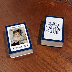 May include: Two navy blue and white matchbox-style boxes. One box has a photo of a young child with the text "Jessica's 30th" and "Vintage 1995". The other box has the text "Dirty Thirty Club" in a script font.