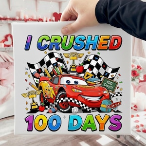 May include: A square canvas print featuring a cartoon of a red race car with the text "I CRUSHED 100 DAYS". The image includes checkered flags, pencils, and a small chalkboard that says "100 Days!".