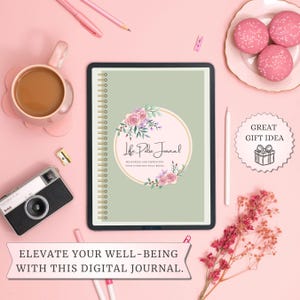 Puede incluir: Un diario digital con un diseño floral y el texto "Life Pulse Journal" sobre un fondo rosa. El diario está rodeado de una taza de café, una cámara, macarons y bolígrafos. También está presente el texto "Eleva tu bienestar con este diario digital".