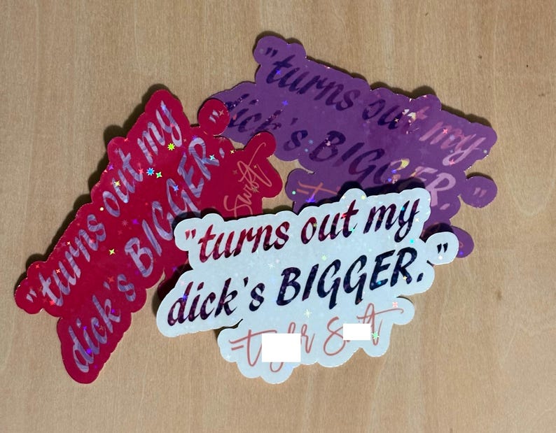 May include: A collection of glittery stickers in red, purple, and white, each featuring the phrase "turns out my dick's BIGGER." The stickers have a holographic effect and are arranged on a light brown surface.