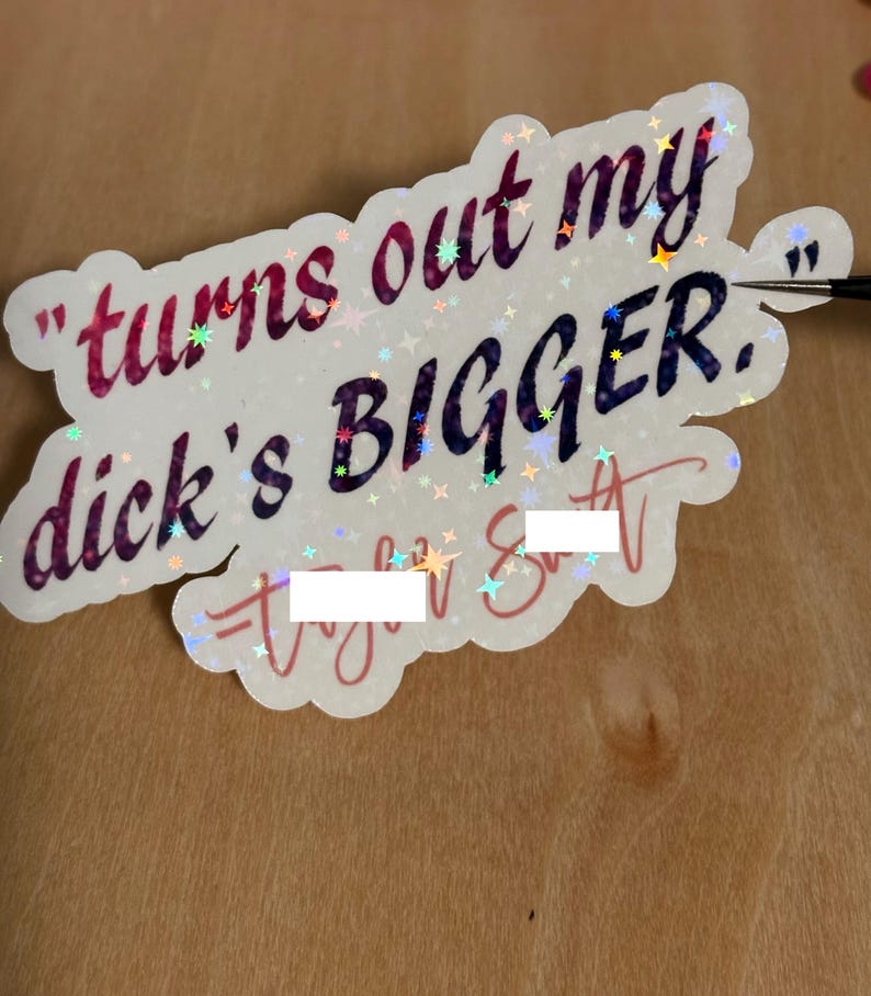 May include: A holographic sticker with the text "turns out my dick's BIGGER." The sticker has a white background with a scalloped edge and is decorated with small star-shaped sparkles. The text is in a mix of colors.