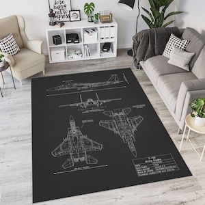 May include: A black rectangular area rug featuring white schematics of an F-15E Strike Eagle fighter jet. The rug includes diagrams and specifications, with dimensions of 420 in / 10.65 m. The rug is placed in a living room setting.