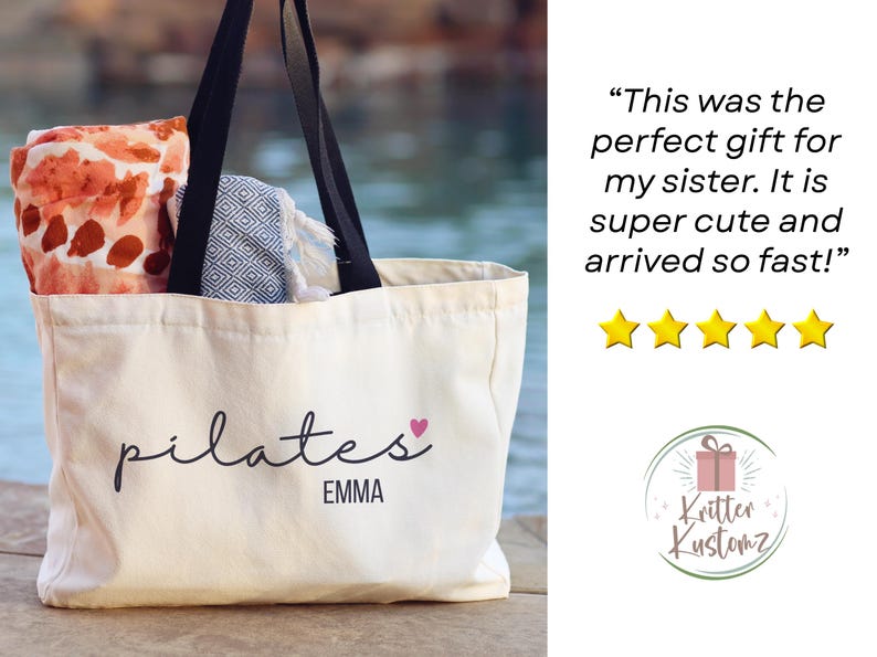 Pu&ograve; includere: Una borsa tote in tela bianca con manici neri che presenta il testo nero pilates ed EMMA con un piccolo cuore rosa. All'interno della borsa ci sono un panno con motivo arancione e bianco e un panno con motivo geometrico blu e bianco.