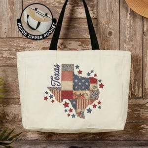 May include: A cream-colored canvas tote bag with black shoulder straps. The front features a graphic of the state of Texas filled with a red, white, and blue patchwork pattern, surrounded by small stars and the word Texas. Includes an inside zipper pocket.