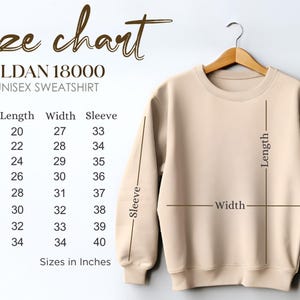 May include: A beige Gildan 18000 unisex sweatshirt hangs on a wooden hanger. The image includes a size chart with measurements in inches for sizes S to 5XL. The chart details length, width, and sleeve measurements.