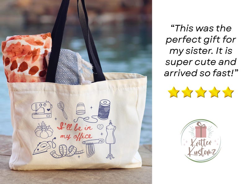 May include: A cream-colored canvas tote bag with black handles, featuring blue and red line art of sewing tools and the text "I'll be in my office." The bag contains a folded orange patterned fabric and a blue and white geometric patterned textile.