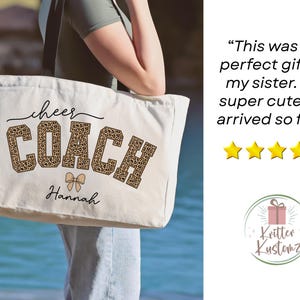 May include: Cream-colored tote bag with the words "cheer COACH" in black and leopard print. The name "Hannah" is printed below the text. A bow graphic is between the words "COACH" and "Hannah".