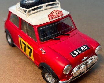 May include: A red toy car with a white roof and black tires on top. The car has the number 177 in yellow on the side and the text "Rallye Monte-Carlo" on the roof. The license plate reads "LBL 6D".