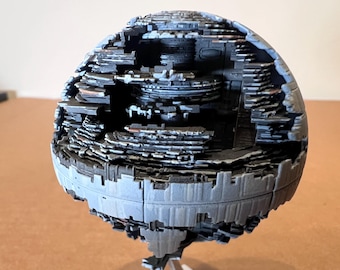 May include: A detailed model of a spherical space station, featuring a cutaway view revealing internal structures. The model is primarily gray with darker gray and black accents, showcasing intricate layers and architectural details. The overall theme is science fiction.