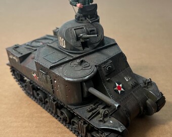 May include: A detailed model of a dark green military tank with a miniature soldier figure in the turret. The tank features a long gun barrel, a star emblem, and intricate track details. The model is painted with weathering effects.