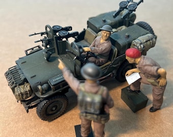 May include: A detailed model of a military jeep with mounted machine guns, featuring three miniature figures in uniform. The jeep is olive green, and the figures are in various poses, suggesting a wartime scene.
