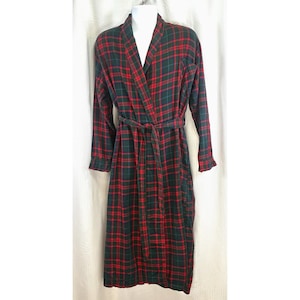 May include: A long, plaid robe in red, green, and black. The robe has long sleeves, a shawl collar, and a matching belt. The robe is displayed on a white mannequin.