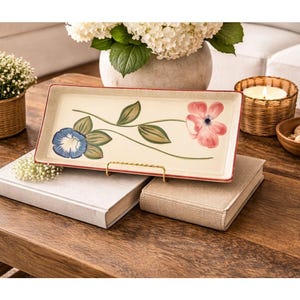 May include: A white ceramic mug with a black handle and the text "But First, Coffee" in a black, handwritten-style font. The mug is on a white surface.