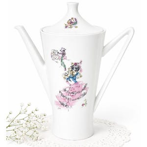 May include: White porcelain coffee pot with a lid, featuring a whimsical watercolor illustration of figures in a pink dress and a castle. The pot has a long spout and a handle that extends from the body.