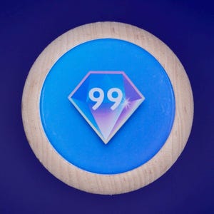 Może przedstawiać: Okrągły drewniany przedmiot z niebieskim środkiem i jasną drewnianą obwódką. Niebieski środek zawiera graficzny diament z liczbą "99" w środku. Tło jest jednolicie ciemnoniebieskie.