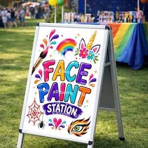 Peut inclure: Panneau en A pour un stand de maquillage. Le panneau présente du texte et des illustrations colorées, dont un arc-en-ciel, une licorne, une toile d'araignée et un œil de tigre. Le panneau est installé sur une pelouse.