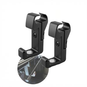 May include: Two black metal brackets with a curved top and a rounded base. Each bracket has a small circular magnet and is attached with a screw. The brackets are designed to attach to a metal surface.