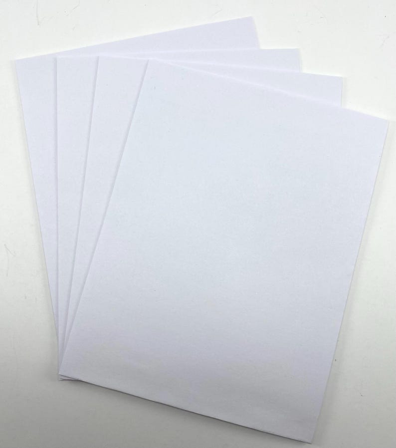 Pode incluir: Uma pilha de folhas de papel brancas e retangulares, ligeiramente em leque. O papel &eacute; branco brilhante e parece liso. As folhas est&atilde;o empilhadas umas sobre as outras, com as bordas vis&iacute;veis.