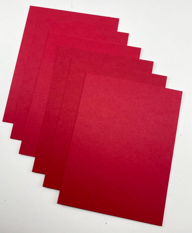 Pode incluir: Uma pilha de folhas de papel vermelho, dispostas em um padr&atilde;o ligeiramente em leque. O papel tem uma textura suave e uma cor vermelha s&oacute;lida e vibrante. As folhas s&atilde;o retangulares e parecem ser de tamanho A4.