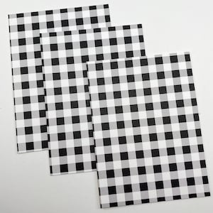 Pode incluir: Tr&ecirc;s folhas de papel retangulares com um padr&atilde;o xadrez preto e branco. O padr&atilde;o consiste em quadrados uniformemente espa&ccedil;ados, criando um design xadrez cl&aacute;ssico. As folhas s&atilde;o dispostas de forma ligeiramente sobreposta, mostrando a repeti&ccedil;&atilde;o do padr&atilde;o.