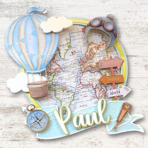 May include: A decorative travel-themed design featuring a hot air balloon, map, compass, and aviator helmet. The design includes the name "Paul" and directional signs with the words "Adventure", "Destiny", and "World". Gold-framed sunglasses are at the top.