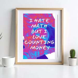 Peut inclure: Une impression d'art encadrée avec un design abstrait coloré. L'œuvre présente le texte "I HATE MATH BUT I LOVE COUNTING MONEY" en blanc sur un fond vibrant de teintes roses, bleues et oranges. L'impression est présentée dans un cadre en bois.