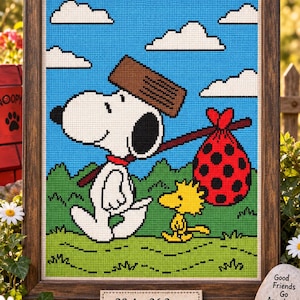 Puede incluir: Un bordado en punto de cruz enmarcado que muestra a Snoopy y Woodstock caminando por un campo verde bajo un cielo azul con nubes blancas. Snoopy lleva un hatillo rojo de lunares. Una etiqueta indica 28,4 x 36,3 cm.