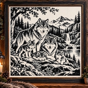 May include: A black and white cross-stitch embroidery depicting a wolf family in a mountainous landscape. The scene features two adult wolves and three pups resting on rocky terrain near a waterfall, framed in a dark wooden square frame.