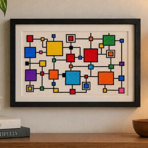 Könnte beinhalten: Ein gerahmtes Kreuzstichbild mit einem geometrischen Muster aus bunten Quadraten und Rechtecken in Rot, Gelb, Blau, Grün, Orange und Violett, die durch dünne schwarze Linien auf einem cremefarbenen Stoffhintergrund verbunden sind.