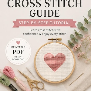 Può includere: Una guida per principianti al punto croce con un tutorial passo passo. L'immagine presenta un cuore ricamato a punto croce in un telaio di legno, filo da ricamo, forbici dorate e il testo "PDF stampabile download immediato."