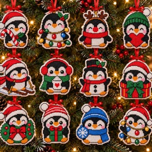 Puede incluir: Una colección de doce adornos navideños de punto de cruz con forma de pingüino, con diversos temas festivos como gorros de Papá Noel, bastones de caramelo, luces, bufandas, esquís, regalos y coronas, cada uno con una cinta roja para colgar.