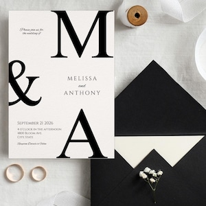 May include: Wedding invitation suite featuring a cream-colored invitation card with black text, including the names "Melissa and Anthony" and the date "September 21 2026." Includes two gold rings, a black envelope, and white ribbon.