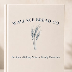 Puede incluir: Un libro de tapa dura color crema con texto azul oscuro y una ilustraci&oacute;n de espigas de trigo. La portada muestra WALLACE BREAD CO. en la parte superior y Recipes &bull; Baking Notes &bull; Family Favorites en la inferior, con una tipograf&iacute;a clara.