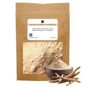 Op de afbeelding: Een bruine papieren zak met Ashwagandha-poeder met een wit etiket. Op het etiket staat "ASHWAGANDHA POWDER" en "100% PURE | NATURAL | RAW PREMIUM QUALITY | GRADE A". Een houten kom bevat het poeder en een bundel ashwagandha-wortels ligt naast de kom.